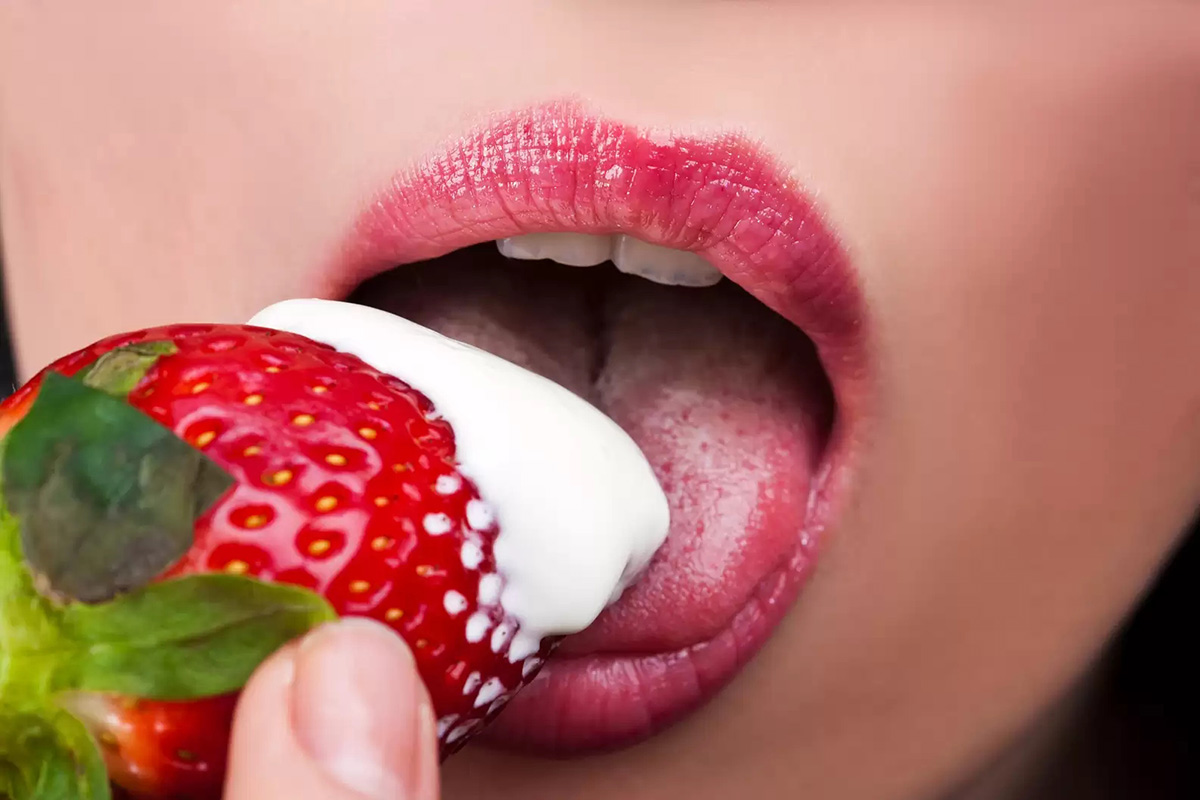 Woman's mouth licking a strawberry